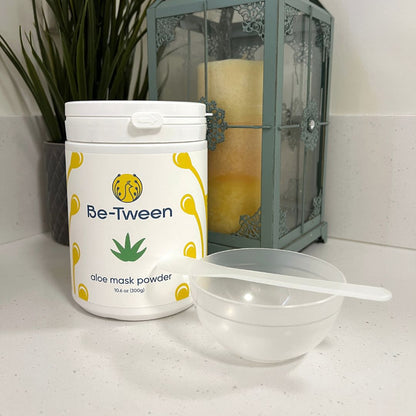 Reusable Facial Mask Mixing Bowl and Spatula Set pictured with Aloe Mask Powder in a bathroom setting. Translucent bowl and spatula placed on a countertop, showcasing a simple and fun tween skincare routine.